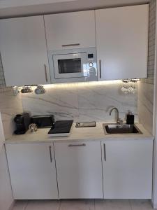 a white kitchen with a sink and a microwave at Vista taurito Ely in Taurito