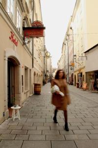 a woman walking down a street in a city at Hotel Krone 1512 in Salzburg