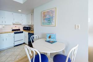 una cocina con mesa y sillas blancas en Golden Sands 809 en Ocean City