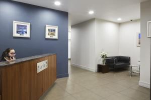 une femme assise au comptoir dans une salle d'attente dans l'établissement Marlin Apartments London City - Queen Street, à Londres