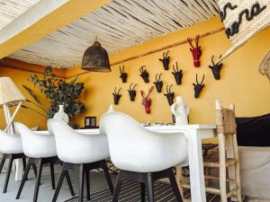 a dining room with white chairs and a wall with antlers at DAR AURORA in Marrakesh