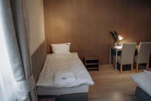 a small room with a bed and a table with chairs at Redwood Hostel in Lublin