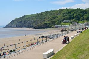 a group of people sitting on benches on a beach at Caban, Pendine Sands in Pendine