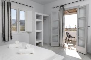 Habitación blanca con cama y silla en Helios Beach Studios, en Plaka