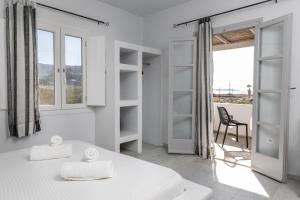 a white room with a bed and a chair at Helios Beach Studios in Plaka