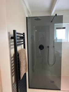 La salle de bains est pourvue d'une douche avec une porte en verre. dans l'établissement Nieuwendamme 88, à Nieuport