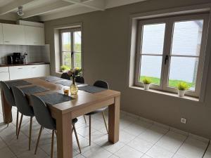 a kitchen with a wooden table and chairs and two windows at Nieuwendamme 88 in Nieuwpoort