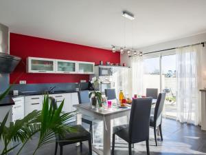 een keuken met rode muren en een tafel en stoelen bij Holiday Home La Goulvinoise - GOV201 by Interhome in Goulven