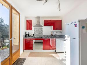a kitchen with red cabinets and a white refrigerator at Apartment La Petite Toscane - CBX100 by Interhome in Cabris