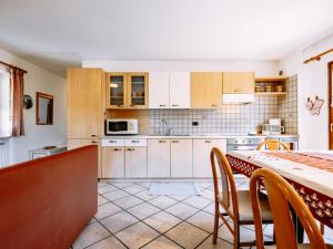 a kitchen with white cabinets and a table with chairs at Apartment Carmen-4 by Interhome in Soraga
