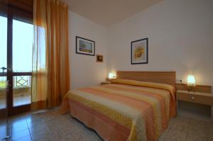 a bedroom with a bed and a large window at Villaggio Selene in Bibione