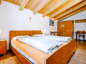 a bedroom with a large bed with a wooden headboard at Apartment Pederiva - SOF743 by Interhome in Soraga