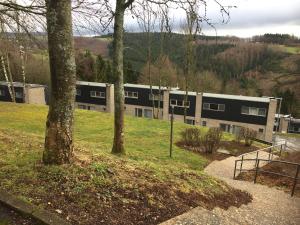 un bâtiment au milieu d'un champ avec des arbres dans l'établissement Les terrasses de Malmedy duplex 420, à Malmedy