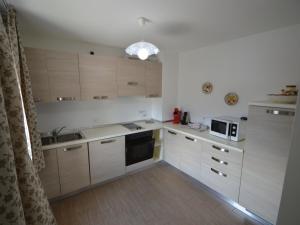 a small kitchen with white cabinets and a microwave at Apartment Casa Rasat-2 by Interhome in Ovasta