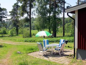 un tavolo con sedie e ombrellone verde e bianco di Chalet Lindby Karneolen - STH151 by Interhome ad Adelsö