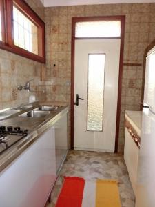 uma cozinha com um lavatório e uma porta branca em Three-Bedroom Villa with garden, parking and ac em Bibione