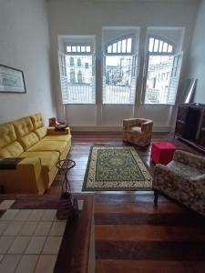 a living room with a yellow couch and chairs at Hostel Nossa Sra de Lourdes in Salvador