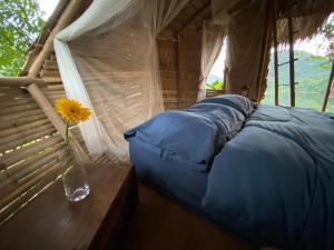 a bedroom with a vase with a flower on a table at Royal mountain Hut in Ratchaburi