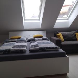 Bett in einem Zimmer mit zwei Kissen und einem Sofa in der Unterkunft Apartmány s výhledem na zámek II in Vimperk