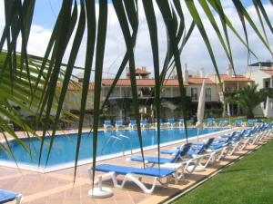 a row of chaise lounge chairs next to a swimming pool at Old Village in Vilamoura
