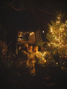 tre bambini in piedi accanto a un albero di Natale di notte di Geo Campers - Full time living camper rental in Kutaisi, Tbilisi, Batumi, Georgia a Kutaisi