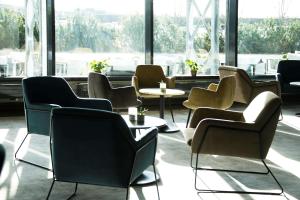 una sala d'attesa con sedie, tavoli e finestre di Park Inn by Radisson Oslo Airport Hotel West a Gardermoen