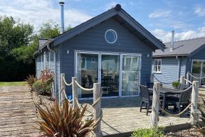 a blue cottage with a deck and a table at Sandy Collection - 2 next door beach houses - Part of the The Bay Filey Holiday Village with pool, gym and direct beach access, pub, restaurant, tennis and meadows walks in Filey