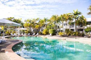 a swimming pool with palm trees in a resort at 1 Bedroom Ground Level Unit in Noosaville Resort in Noosaville