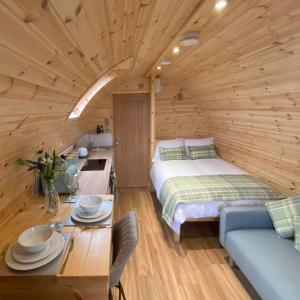 a bedroom in a log cabin with a bed and a table at Meall Ard Self Catering Pod - Isle of South Uist in Pollachar