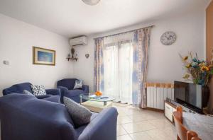 uma sala de estar com sofás azuis e uma televisão em Apartment in Porec/Istrien 35353 em Porec