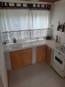 a kitchen with a sink and a stove and a window at Alojamiento Río Fenix Chico in Perito Moreno