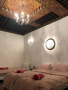 a bedroom with two beds and a ceiling with a chandelier at Dar Naima in Fez