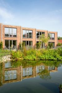 a brick building next to a body of water at Köhlers Forsthaus Wellness & Genuss Hotel in Aurich