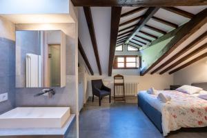 Apartamentos Los Edules في Treceño: غرفة نوم مع سرير وحوض استحمام ومغسلة