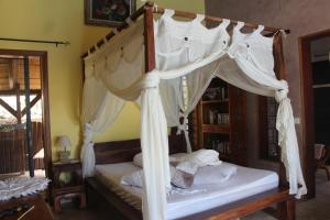 sypialnia z łóżkiem z baldachimem i białymi zasłonami w obiekcie LA LIANE DE JADE 974-Lodge Le Palissandre - jacuzzi privatif - piscine w mieście Le Bois de Nèfles