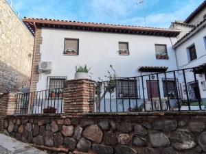 una casa bianca con una recinzione e un muro di pietra di Casa Alfonso Toledo Más que una casa un hogar a Toledo
