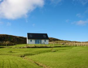 a house on a hill with a green field at Atlantic Drift - Isle of Skye - Amazing Sea views in Glendale