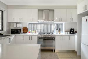 een keuken met witte kasten en een fornuis met oven bij Stylish 4BR Villa with Office l Modern and Comfy in Marsden Park