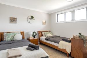 een slaapkamer met 2 bedden en een raam bij Stylish 4BR Villa with Office l Modern and Comfy in Marsden Park