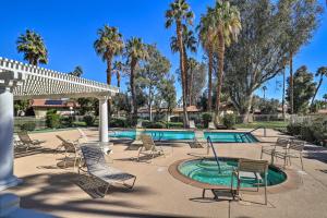 a patio with chairs and a swimming pool with palm trees at Palm Desert Vacation Rental with Pool Access! in Palm Desert