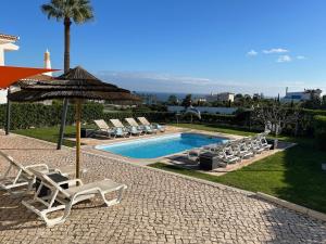 a group of chairs and an umbrella next to a swimming pool at Villa Bellevue 4 in Albufeira