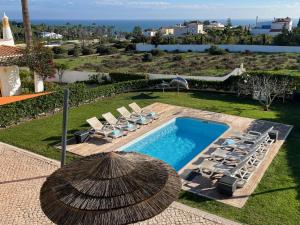 a pool with lounge chairs and a straw umbrella at Villa Bellevue 4 in Albufeira