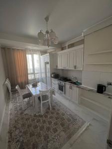 a kitchen with white cabinets and a table and chairs at 3-room elite apartment Alexandria in Bishkek