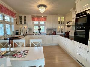 a kitchen with white cabinets and a table with chairs at Holiday home Sæbøvik in Sæbøvik