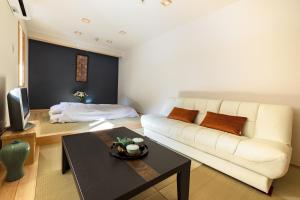 宿坊 志摩房 - Temple Hotel Simanobo في Minobu: غرفة معيشة مع أريكة بيضاء وطاولة