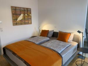 a bed with orange pillows and a picture on the wall at Trilogie am See Wohnung Ranke in Stetten