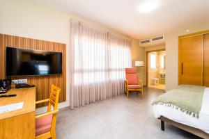 a hotel room with a bed and a desk and a television at Hotel Vistamar Wellness by DLV in Villajoyosa