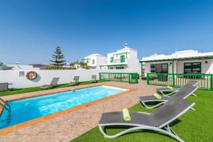 a swimming pool with chairs and a house at Villa Mero in Playa Blanca
