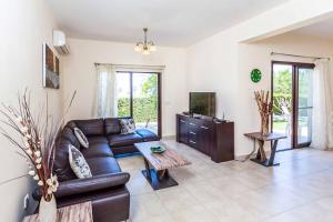 een woonkamer met een leren bank en een tv bij Villa Lara Latchi in Lachi