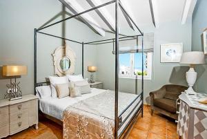 a bedroom with a canopy bed and a chair at Bini Cel in Binibeca